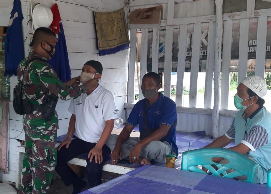 Saat Komsos, Sertu Ardian Agus Pakaikan Masker Ke Warga