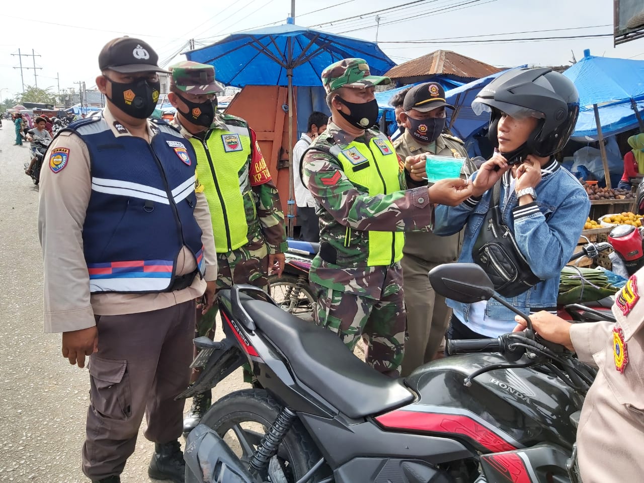 Usai Ditegur, Serda Sarju Pasangkan Masker ke Masyarakat